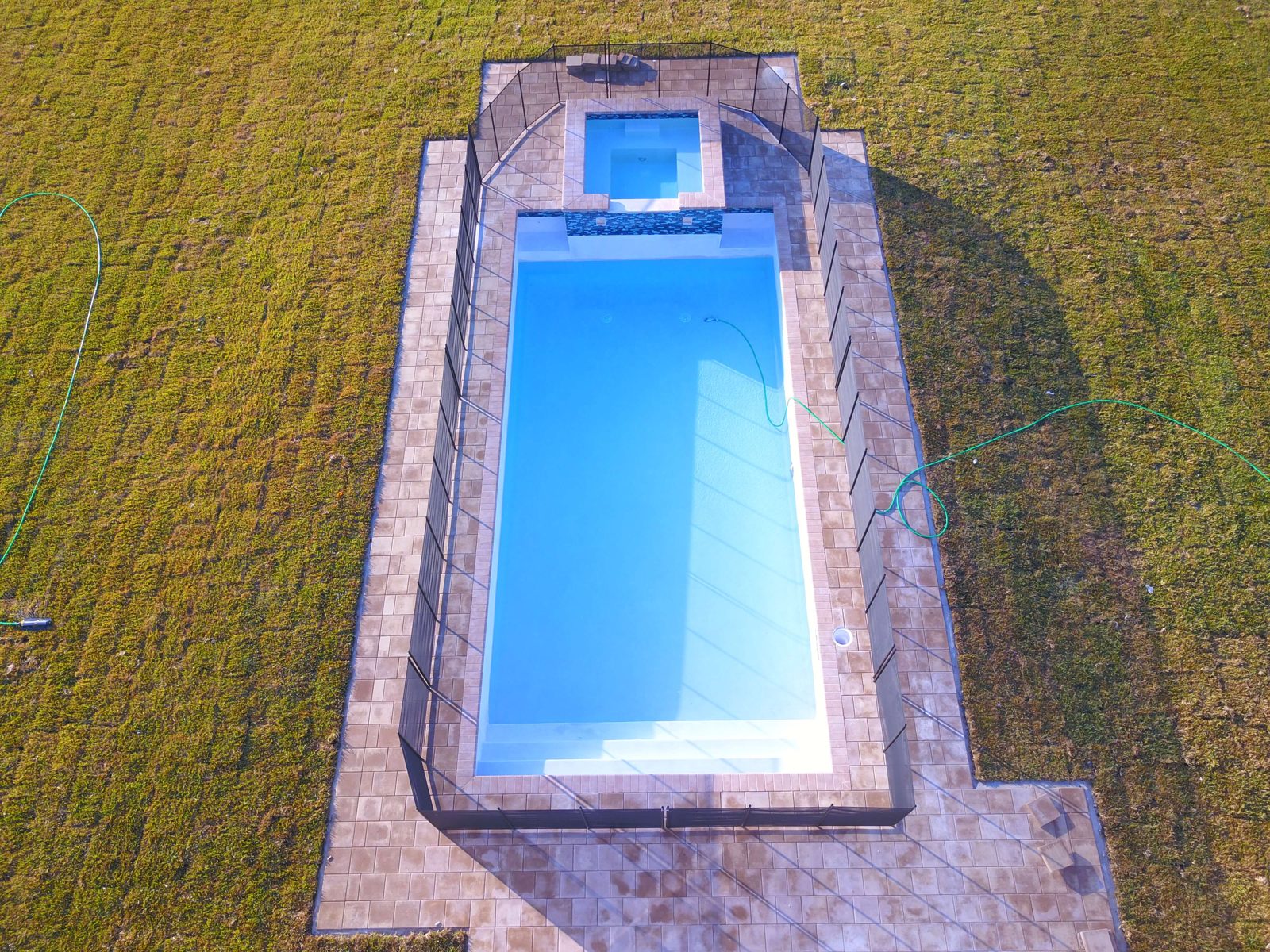 Aerial view of a new pool and spa with paver deck
